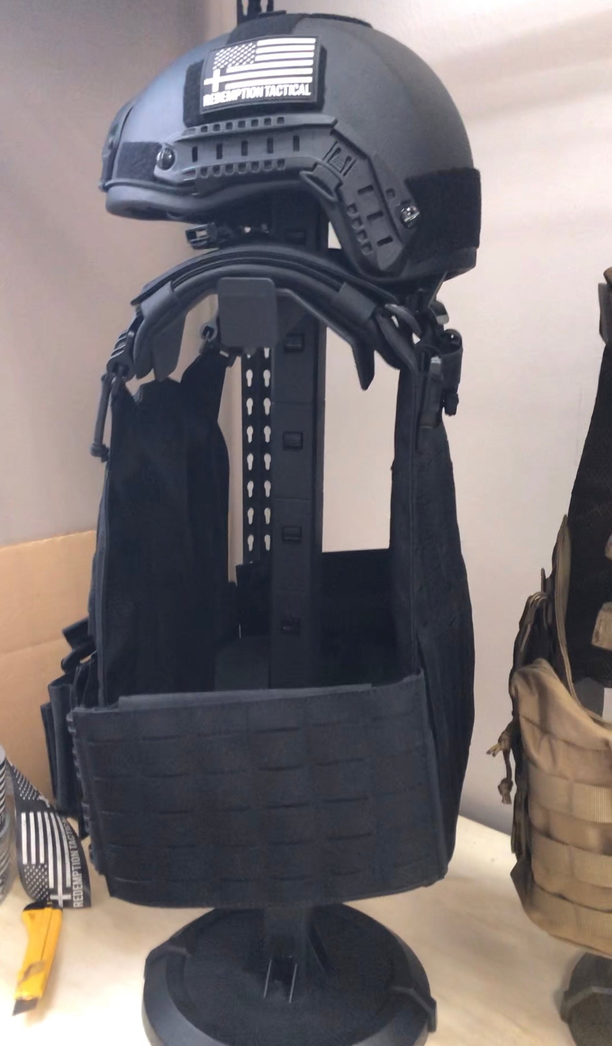 Green Tip Surplus Armor Butler Stand 2.0, designed for holding tactical vests, helmets, and battle belts. This heavy-duty stand can be customized to display or deploy armor quickly, and comes in black and coyote brown colors.